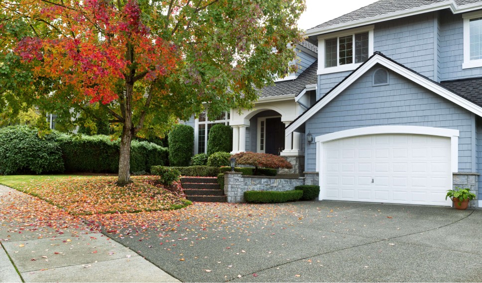 Home exterior with the garage door closed and fall leaves on the ground
