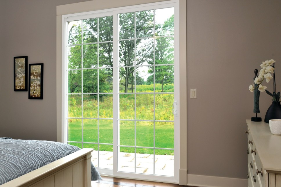 Naturally lit bedroom with gray walls and a sliding patio door overlooking a spacious area of land
